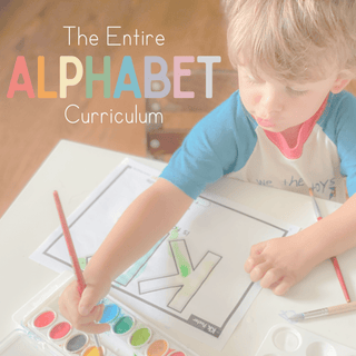 Toddler painting while exploring the Entire Alphabet Curriculum with colorful letters and art supplies.