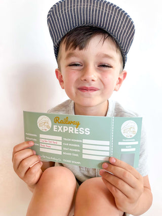 Smiling child holding a Railway Express ticket for the T is for Train Kit, promoting playful learning and creativity.