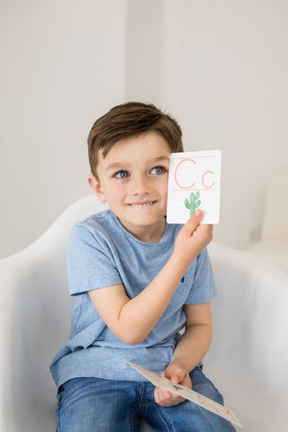 Smiling boy holding a flash card with the letter