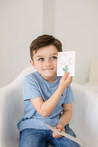 Smiling boy holding a flash card with the letter