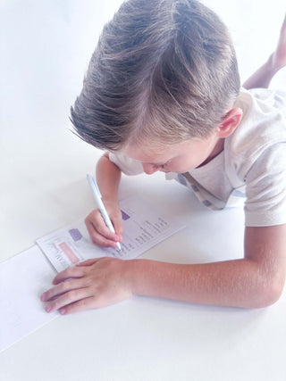 Boy writing on paper with a pen, engaged in creative activities and learning.