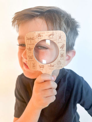 Preschooler using a magnifying glass to explore bugs during outdoor science play