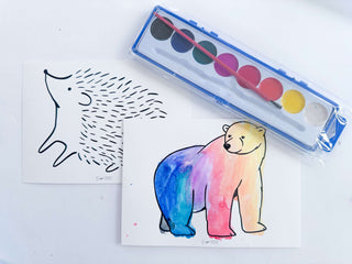 Watercolor paints and animal-themed paper for creative activities in preschool hibernation kit