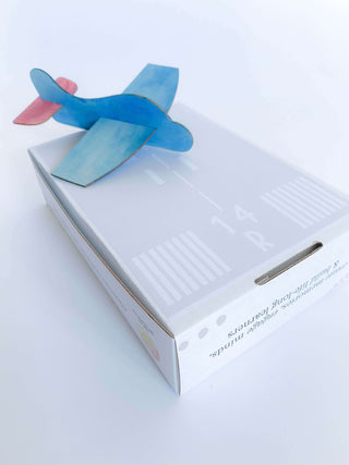 Airplane play and learn kit for kids, offering supplies to create and race four different airplanes. Includes wooden airplane craft, paper airplane, straw airplane, position words playdough mats, and a children