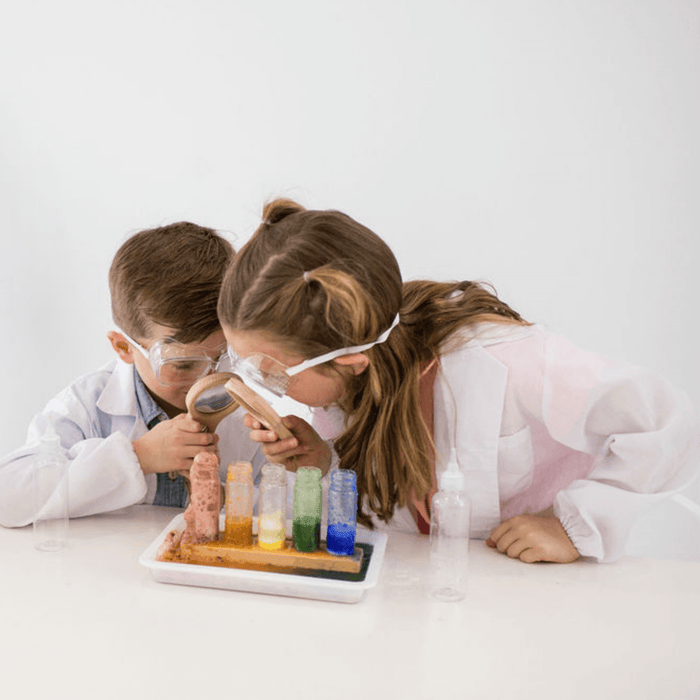 Two children in safety goggles mixing colors in test tubes for the Science kit.